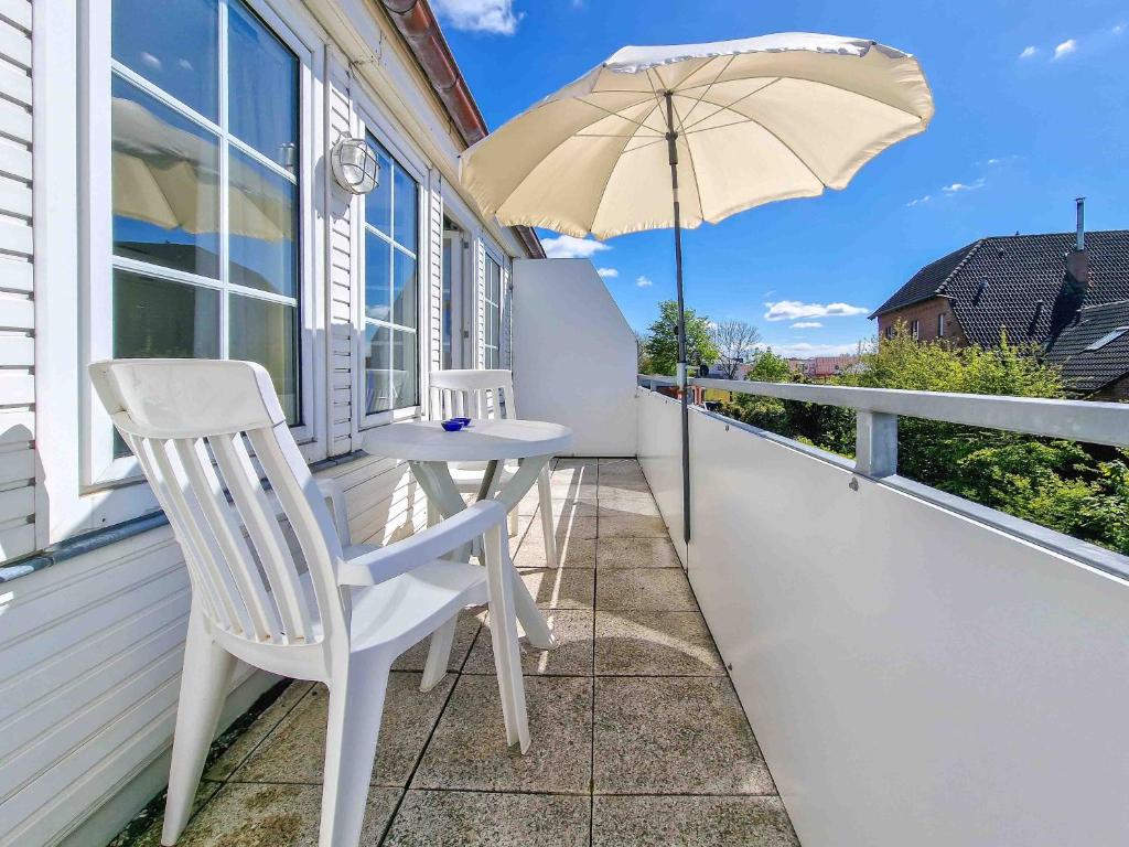 een balkon met een tafel en een parasol bij Moin in Greetsiel