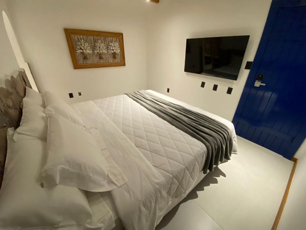 a bedroom with a white bed and a television at Villa Hortensia in Mucugê
