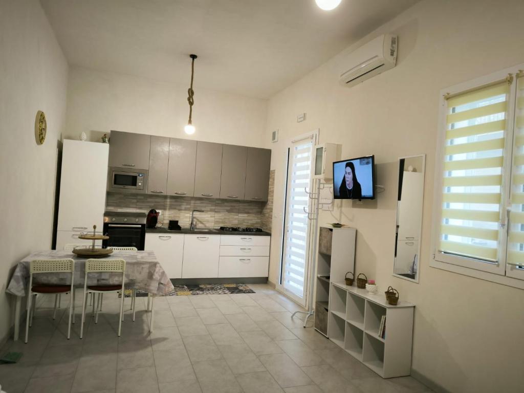 een keuken met een tafel en een keuken met witte kasten bij Da nonna Concetta in Donnalucata