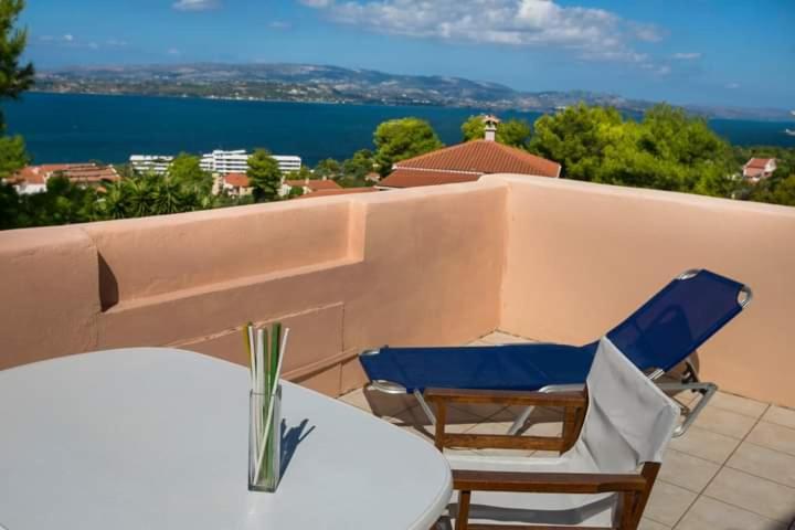 two chairs and tables on a balcony with a view of the water at Αngelika studios in Argostoli