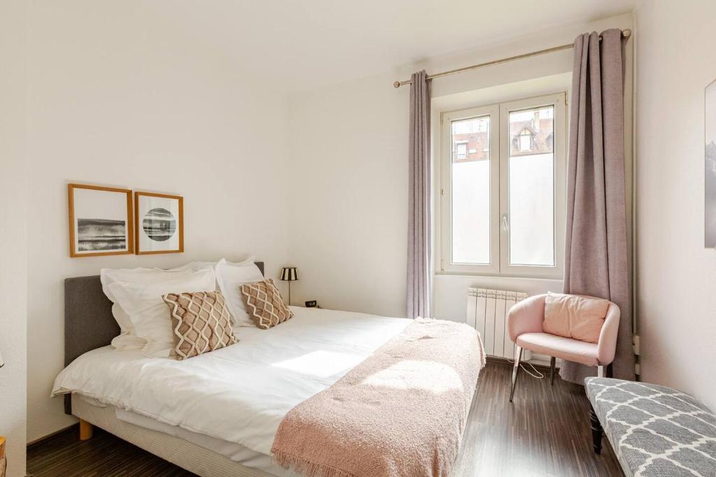 a white bedroom with a bed and a pink chair at MAMRAY in Colmar