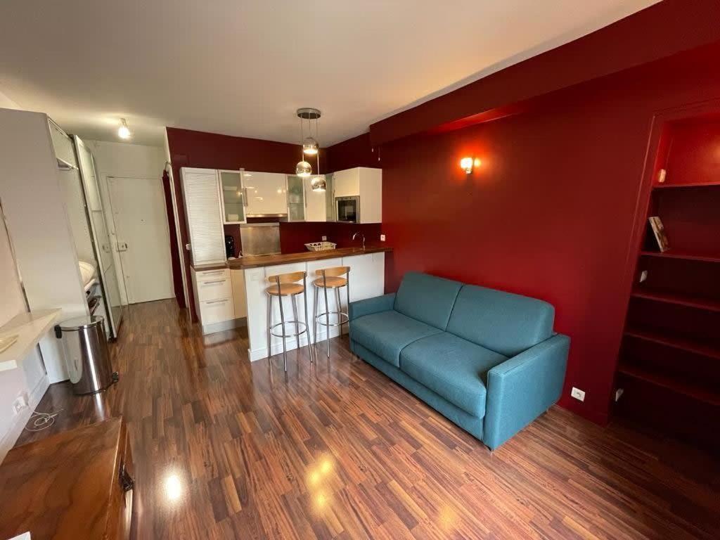 a living room with a blue couch and a kitchen at Studio Jean Mermoz CityCosy in Paris