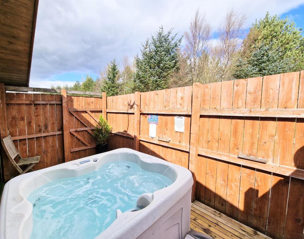 a hot tub in a backyard with a wooden fence at Lomond 5 with Private Hot Tub - Fife - Loch Leven - Lomond Hills - Pet Friendly in Kelty