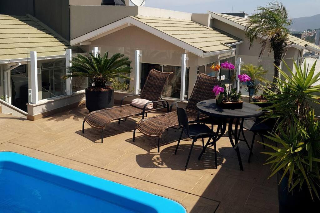 um pátio com uma mesa e cadeiras ao lado de uma piscina em Campinas Penthouse - Cobertura Luxo com Piscina Privativa em São José