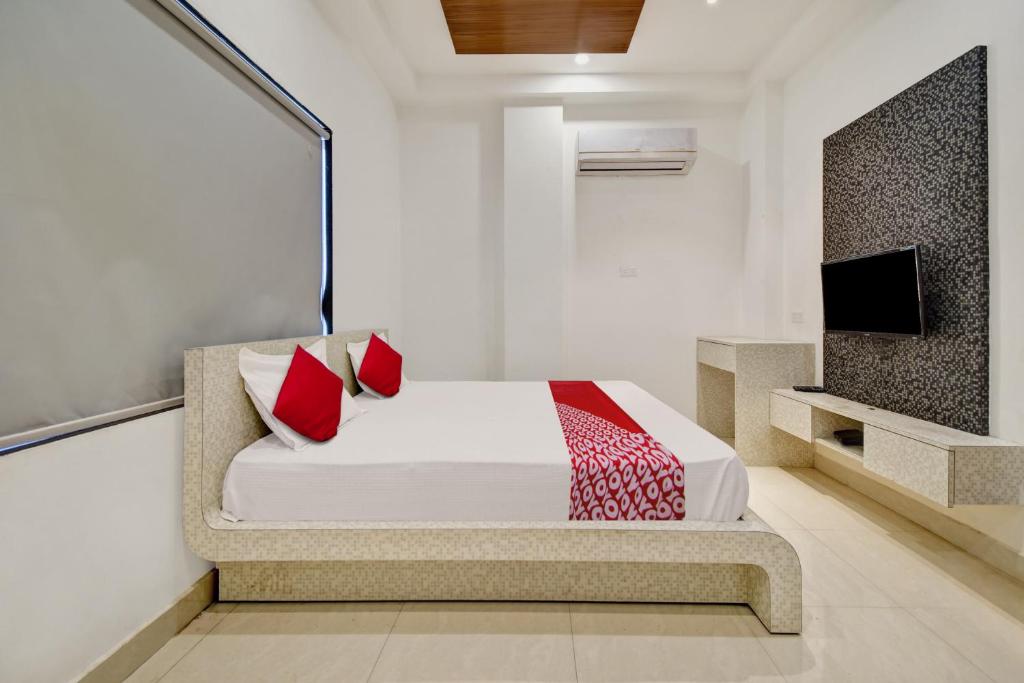 1 dormitorio con 1 cama con almohadas rojas y TV en OYO Flagship Hotel Laxmi Inn en Kota