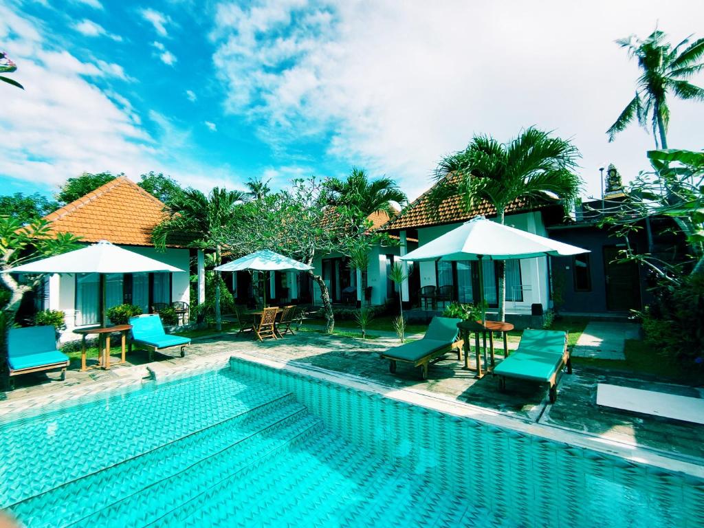 a swimming pool with chairs and umbrellas next to a house at Tunjung Kuning Cottage in Nusa Penida