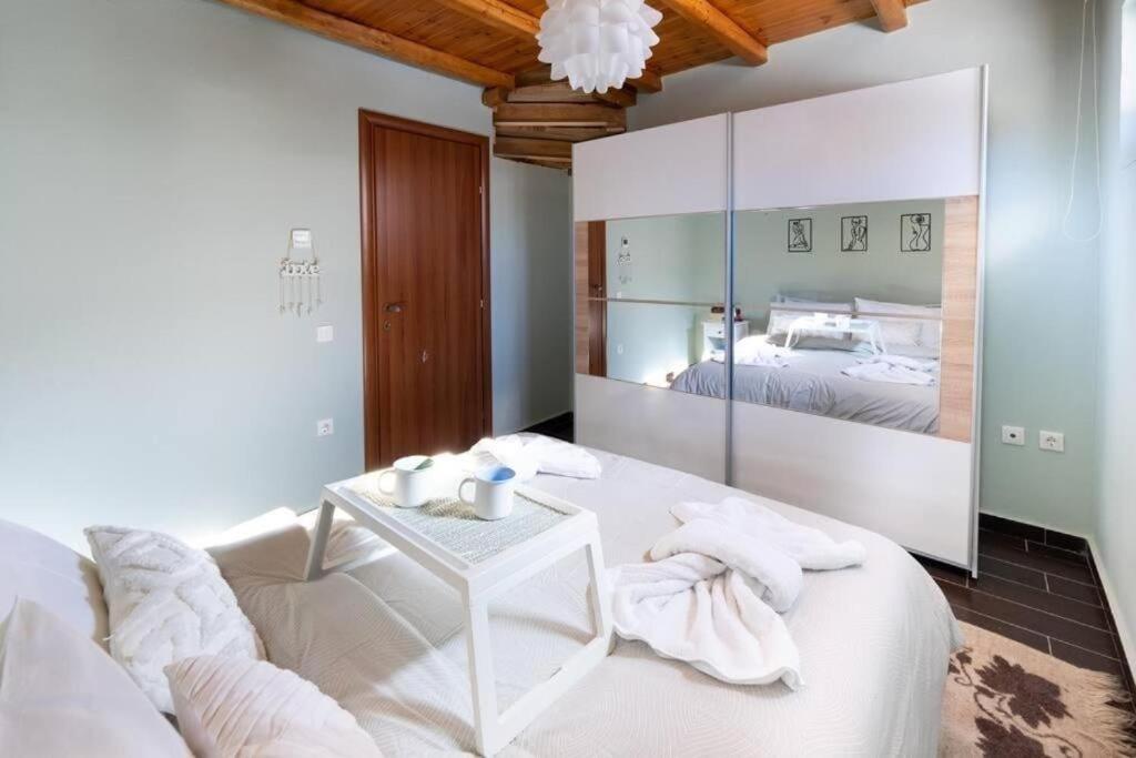 a white bedroom with a bed and a table at Kaimaktsalan maisonette in Palaios Agios Athanasios
