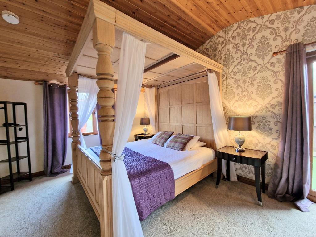 a bedroom with a canopy bed and a table with a lamp at Lomond 6 with Private Hot Tub - Fife - Loch Leven - Lomond Hills in Kelty