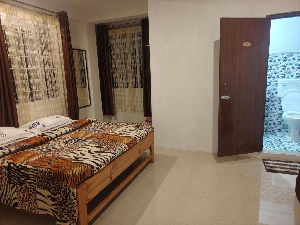 een slaapkamer met een bed en een deur naar een toilet bij Breeze Hills Inn in Cherrapunji