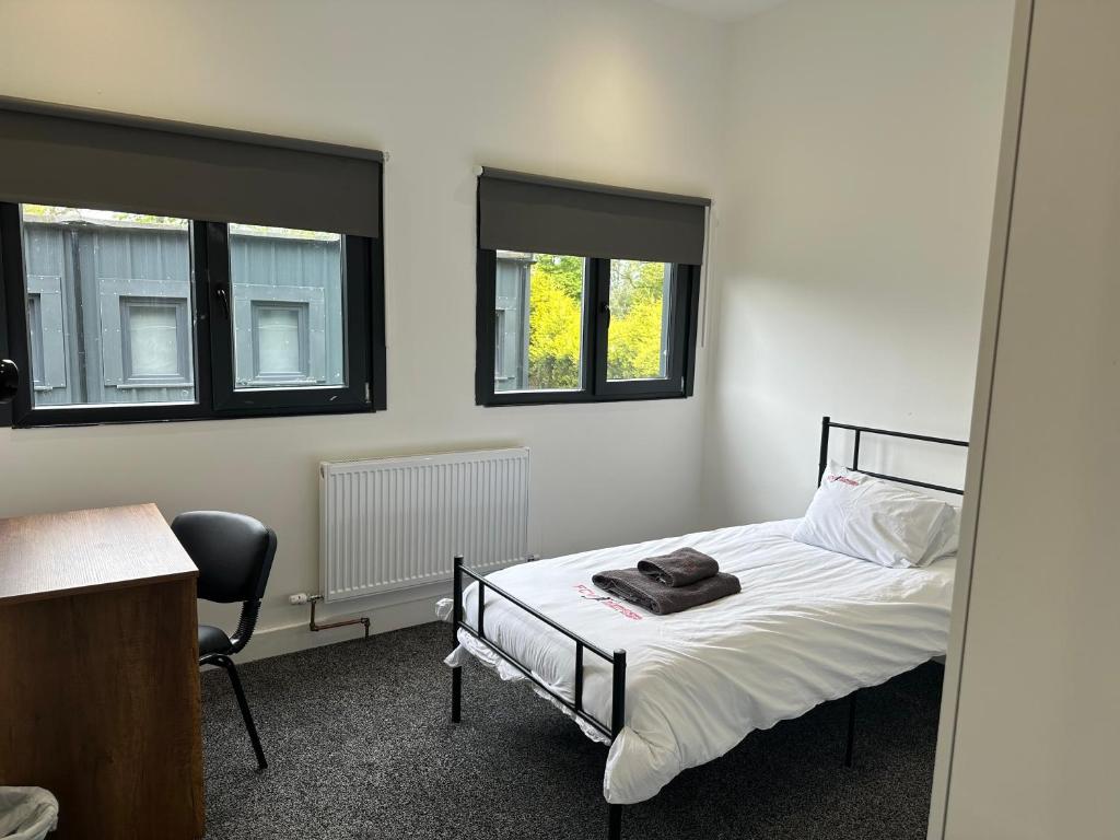 a bedroom with a bed and a chair and two windows at Grace Dieu Manor Park in Thringstone