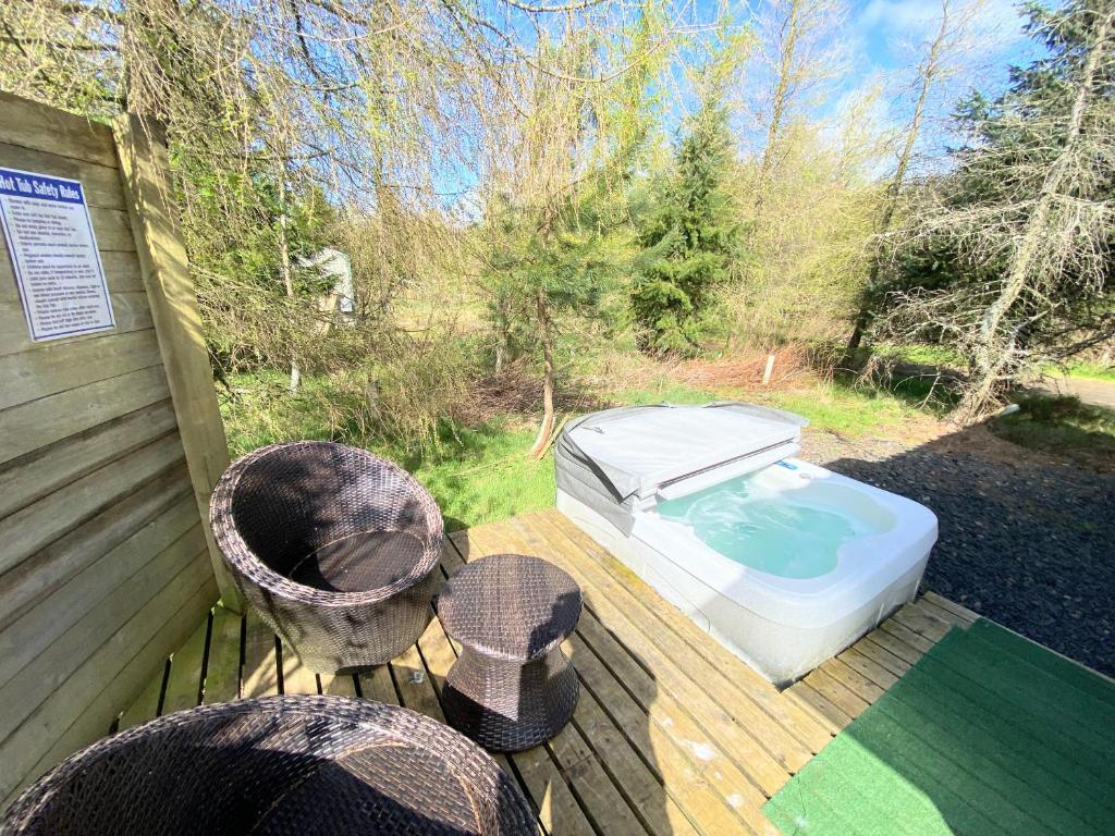 a hot tub sitting on a deck with two chairs at Blair Tiny House with Private Hot Tub - Pet Friendly- Fife - Loch Leven - Lomond Hills in Dunfermline