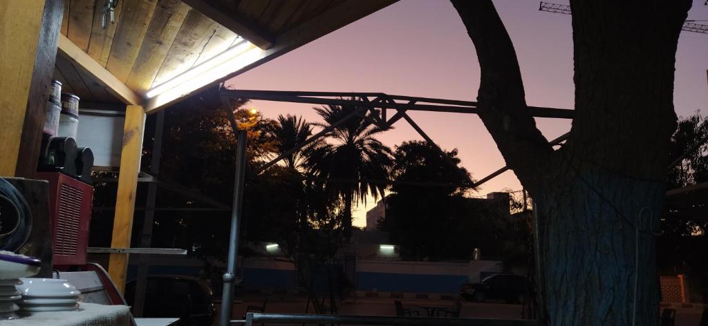 ein Gebäude mit einem Baum vor einem Sonnenuntergang in der Unterkunft Auberge-Cafe Tunisie in Nouakchott