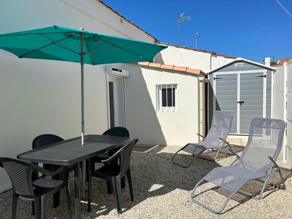 une table avec des chaises et un parasol sur une terrasse dans l'établissement Maison * 2/4 pers* Jard sur Mer, à Jard-sur-Mer