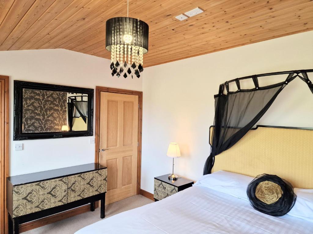a bedroom with a bed and a chandelier at Torridon 12 with Private Hot Tub - Fife - Loch Leven - Lomond Hills in Kelty