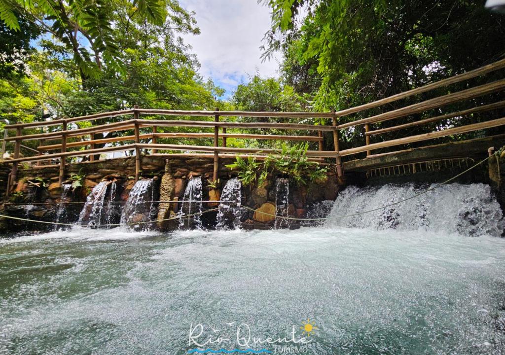 a wooden bridge over a waterfall in a park at Thermas Paradise Residence in Rio Quente