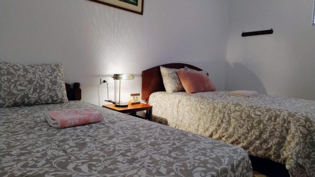 Habitación con 2 camas y mesa con lámpara. en Hospedaje Boutique LEOS EIRL, en Lima