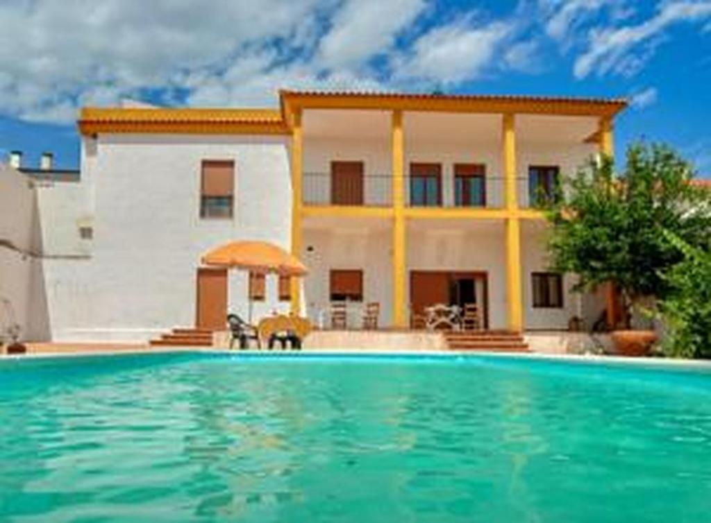 a villa with a swimming pool in front of a house at El Retiro Vivienda Rural in Villanueva del Rey