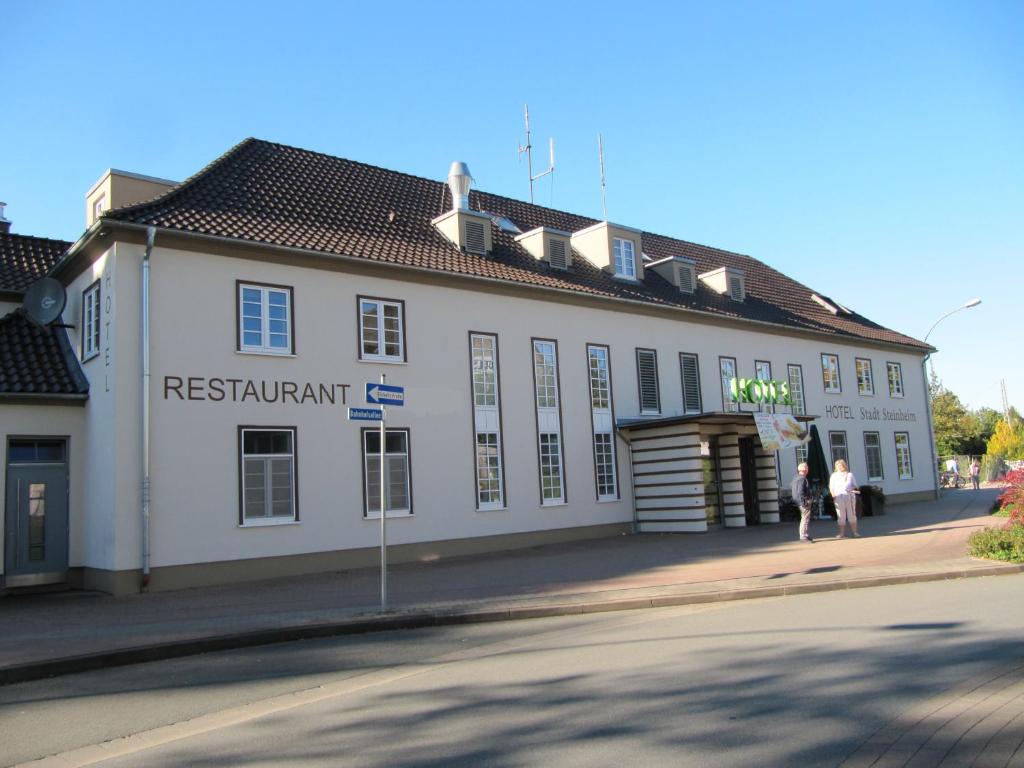Ein weißes Gebäude mit Leuten, die davor laufen. in der Unterkunft Hotel Stadt Steinheim in Steinheim