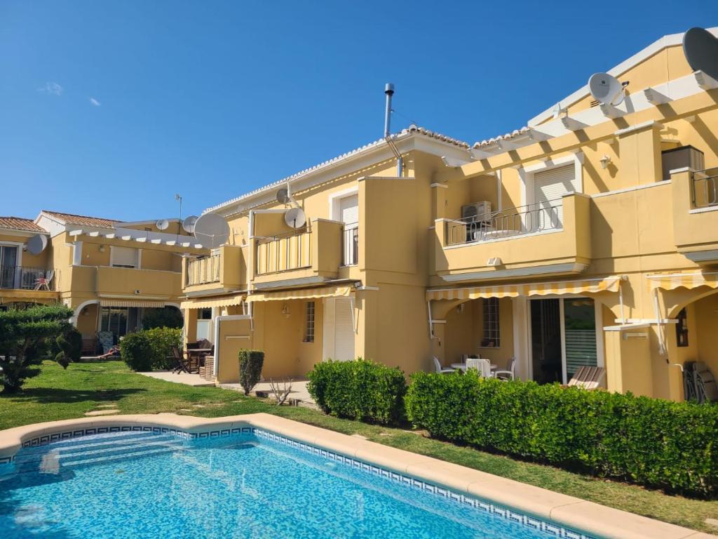 uma casa grande com uma piscina em frente em Bungalow Aldea del Mar em Els Poblets