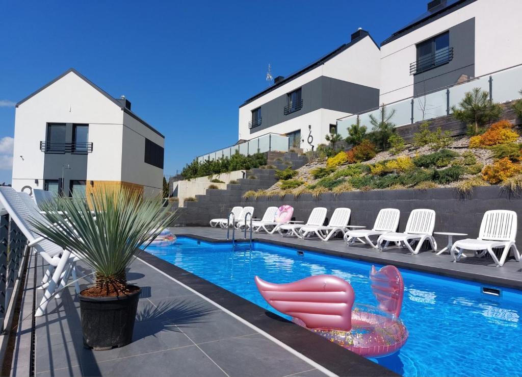 a swimming pool with lounge chairs next to a building at Klif Resort Apartamenty in Mechelinki