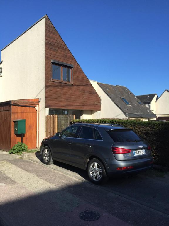 une voiture noire garée devant une maison dans l'établissement Cottage de la Mer, au Crotoy