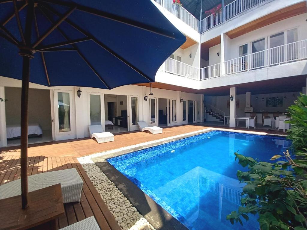 - une grande piscine avec un parasol à côté d'une maison dans l'établissement Lumiere Hotel Gili Trawangan, à Gili Trawangan