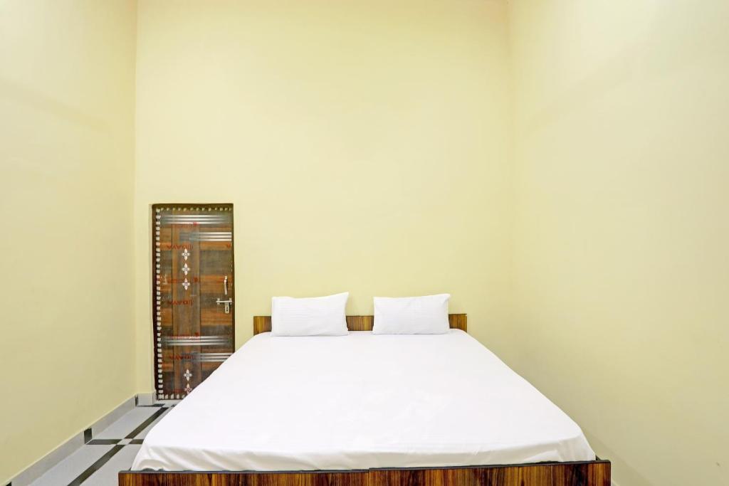 a bedroom with a bed with white sheets at OYO J.M.D Restaurant &rooms in Jhājhar