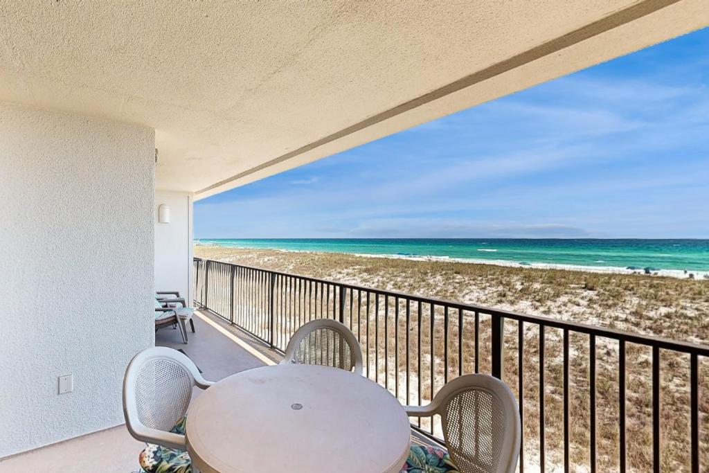 een balkon met een tafel en stoelen en het strand bij Emerald Surf 102 in Navarre
