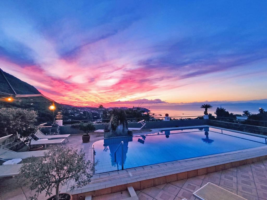 a swimming pool with a sunset in the background at Hotel Ape Regina in Ischia