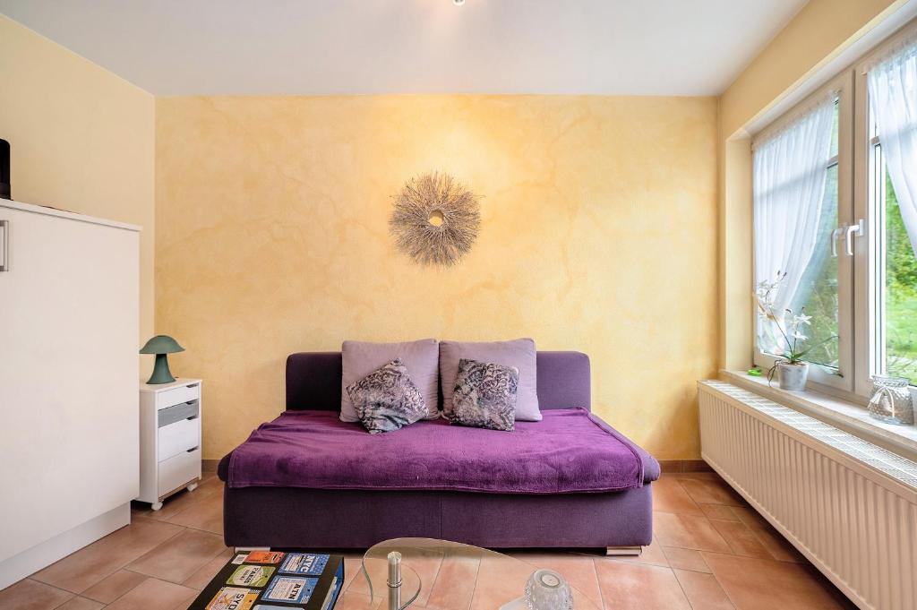 a purple couch in a room with a wall at Gästehaus Mühlenhof - Müller-Thurgau in Maring-Noviand