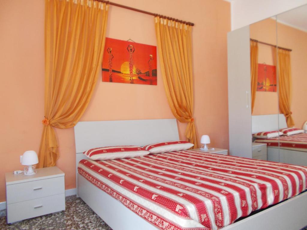 アッリステにあるAppartamenti Blue Houseのベッドルーム1室(オレンジ色のカーテンが付いた大型ベッド1台付)