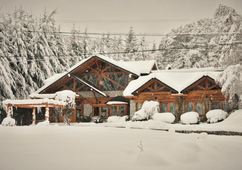 uma cabana de madeira na neve com neve em ONA Apart Hotel and Spa em Villa La Angostura
