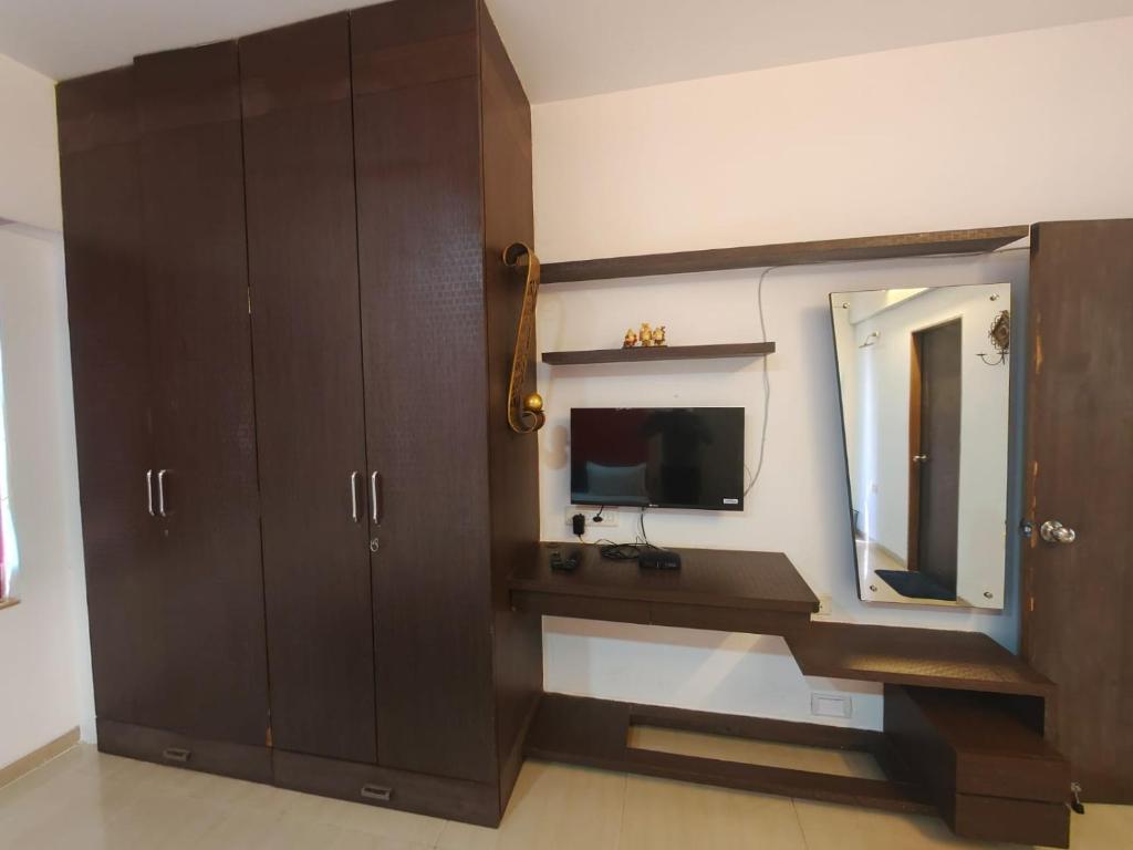 baño con tocador con espejo y TV en Quality Hospitality Services, en Pune
