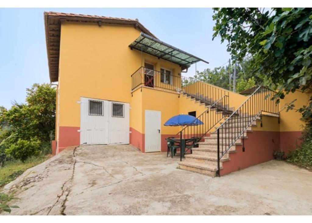 a house with a staircase and a table with an umbrella at El Trabaz in Candamo