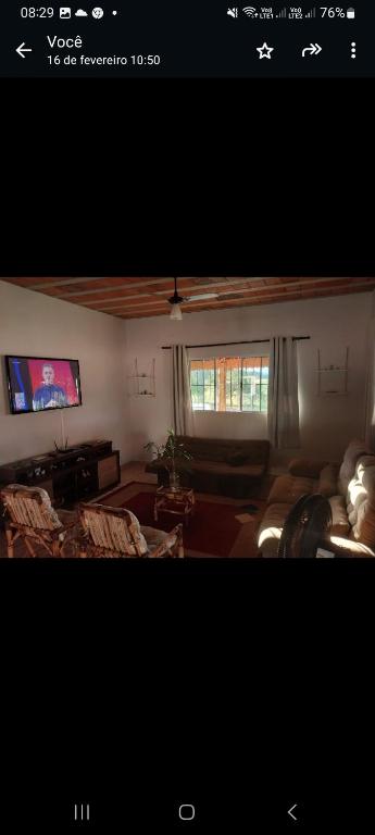 a living room with a couch and a tv at Chácara cantinho da paz in Quadra
