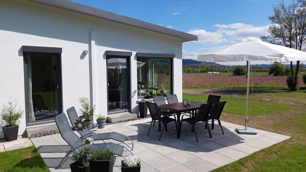 eine Terrasse mit einem Tisch, Stühlen und einem Sonnenschirm in der Unterkunft Ferienhaus Casa Neugrua in Stockheim