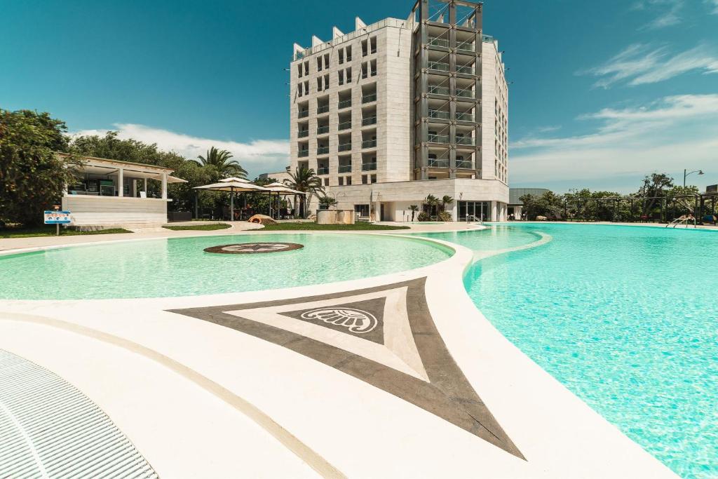 uma grande piscina com um edifício ao fundo em Delta Hotels by Marriott Olbia Sardinia em Olbia