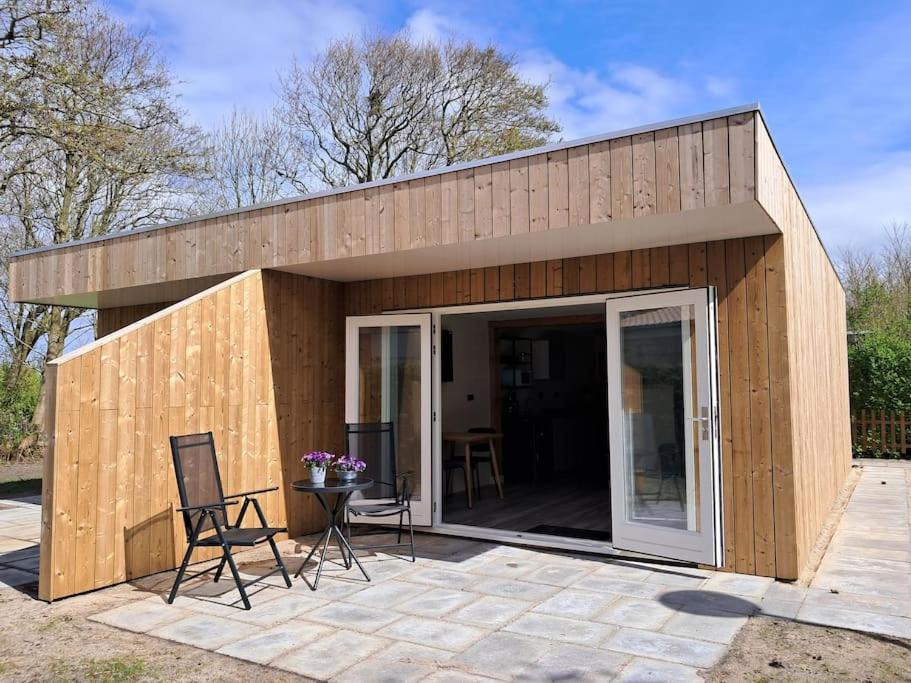 a small building with two chairs and a patio at Strandhuisje EVA, dicht bij zee in Callantsoog