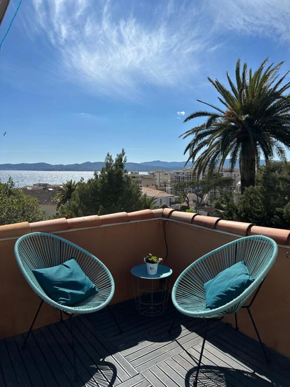 - un balcon avec 2 chaises, une table et un palmier dans l'établissement ESTEREL BELAHOME Charmant 3 pièces St Raphael Vue Mer, à Saint-Raphaël