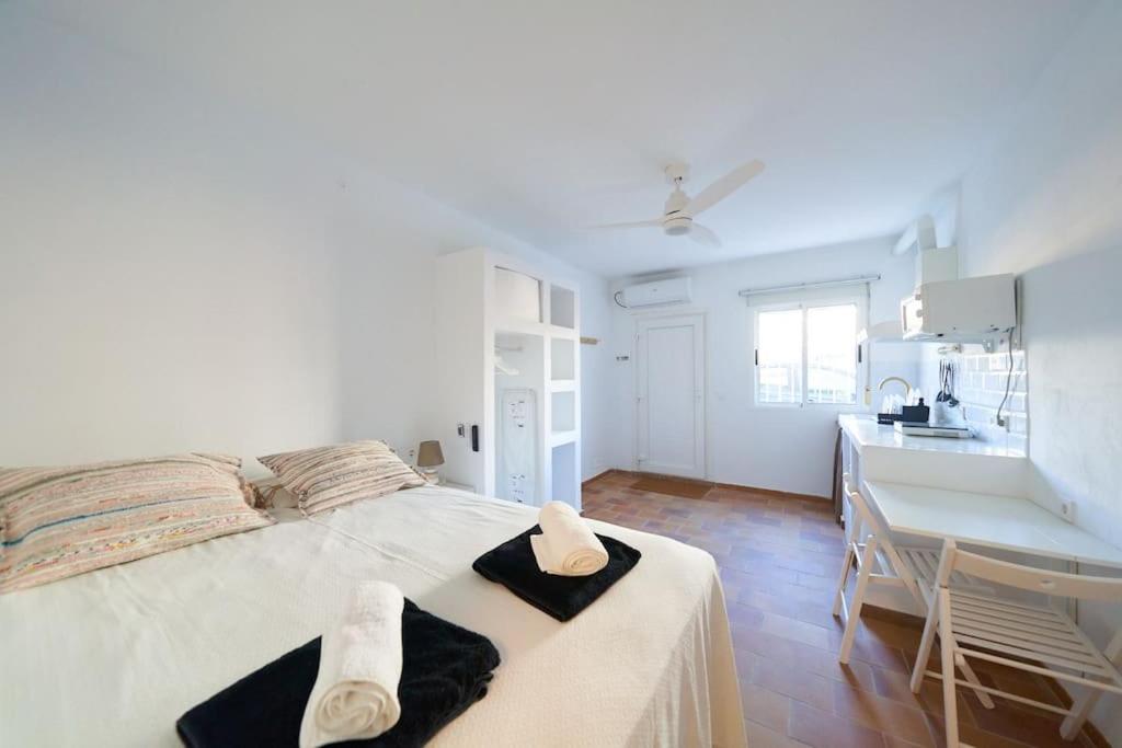 a white bedroom with a bed and a kitchen at Lirondo in San José