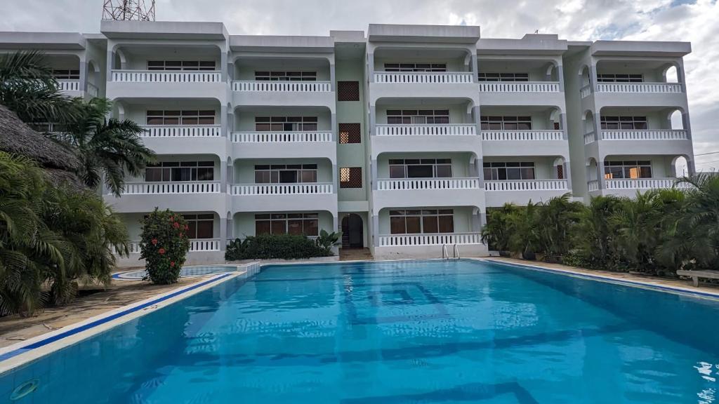 un hotel con piscina frente a un edificio en Nightingale Apartments Hotel Mombasa, en Shanzu