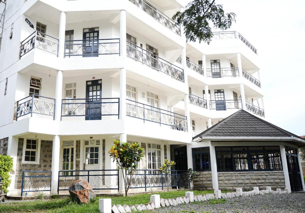 einen Blick nach außen auf ein weißes Gebäude in der Unterkunft Queen's Way Resort in Kisumu