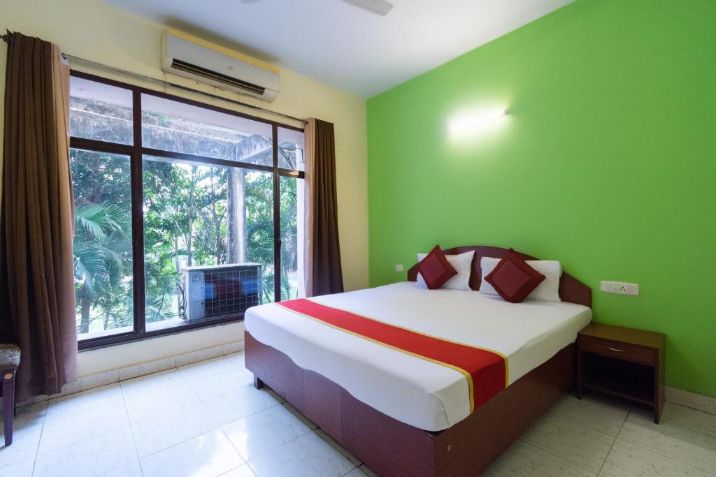 a bedroom with a bed with green walls and a window at Lake View Resort in Kolkata