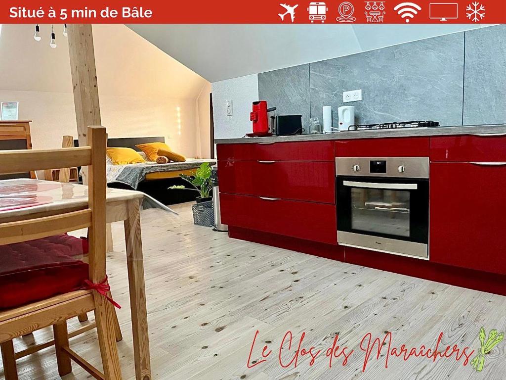 kuchnia z czerwonymi szafkami, kuchenką i stołem w obiekcie Le Clos des Maraîchers w mieście Village-Neuf