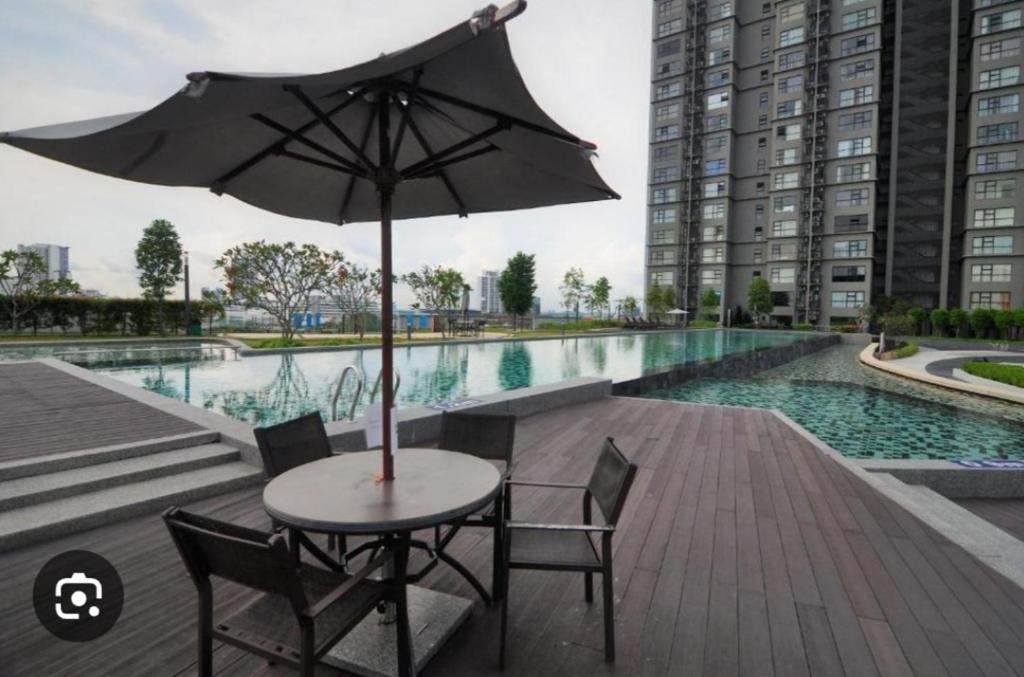 een tafel en stoelen met een parasol naast een zwembad bij Hyve in Cyberjaya