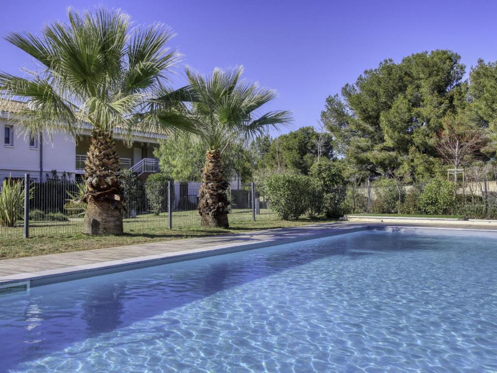 ein Pool mit zwei Palmen vor einem Haus in der Unterkunft Apartment Les Terrasses d'Azur-2 by Interhome in Sanary-sur-Mer