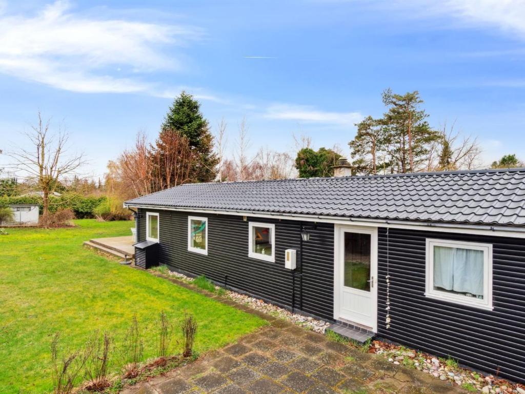 a black house with a yard in front of it at Holiday Home Kara - all inclusive - 450m from the sea by Interhome in Gilleleje