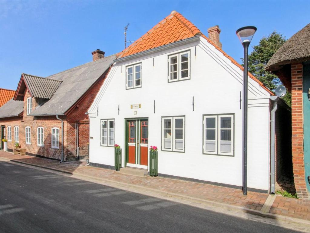 uma casa branca com portas vermelhas numa rua em Holiday Home Odeta - all inclusive - 25km from the sea by Interhome em Højer