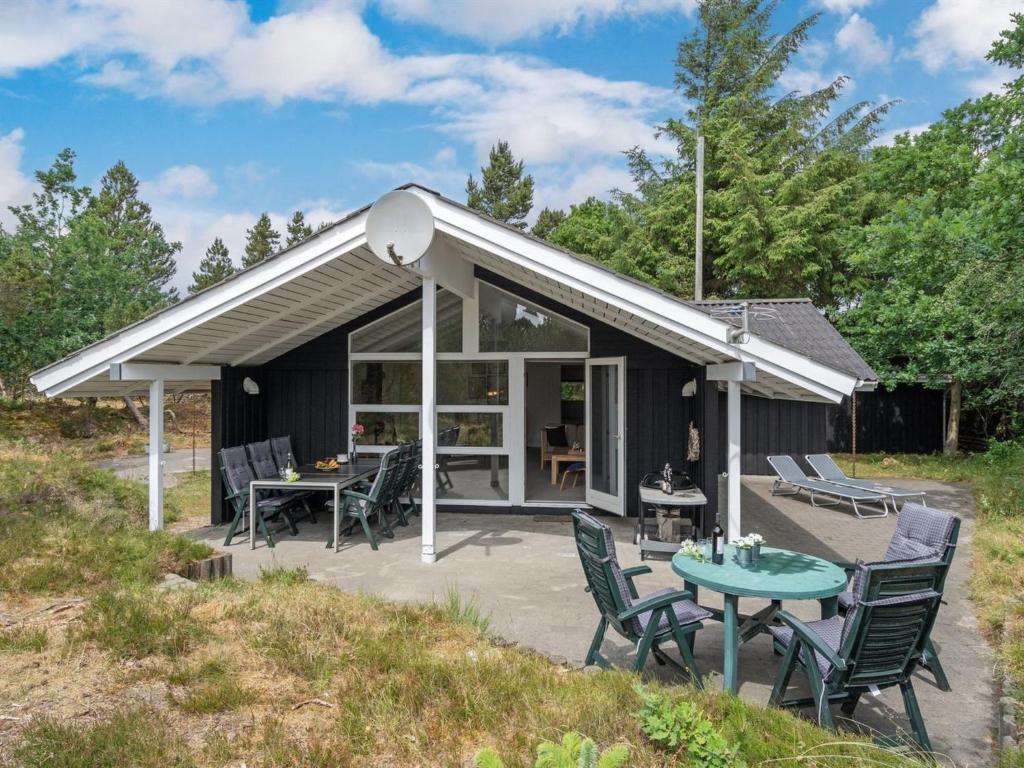um pavilhão com uma mesa e cadeiras e um pátio em Holiday Home Jannick - all inclusive - 1-5km from the sea by Interhome em Blåvand