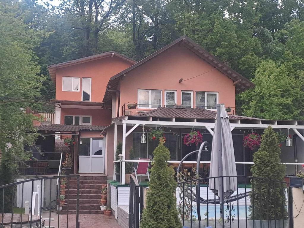 une maison rose avec un parasol devant elle dans l'établissement Casa de vacanță MARA emd, à Eşelniţa